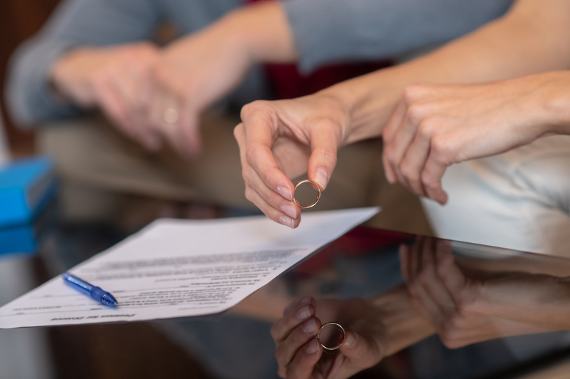 holding wedding ring and signing divorce papers